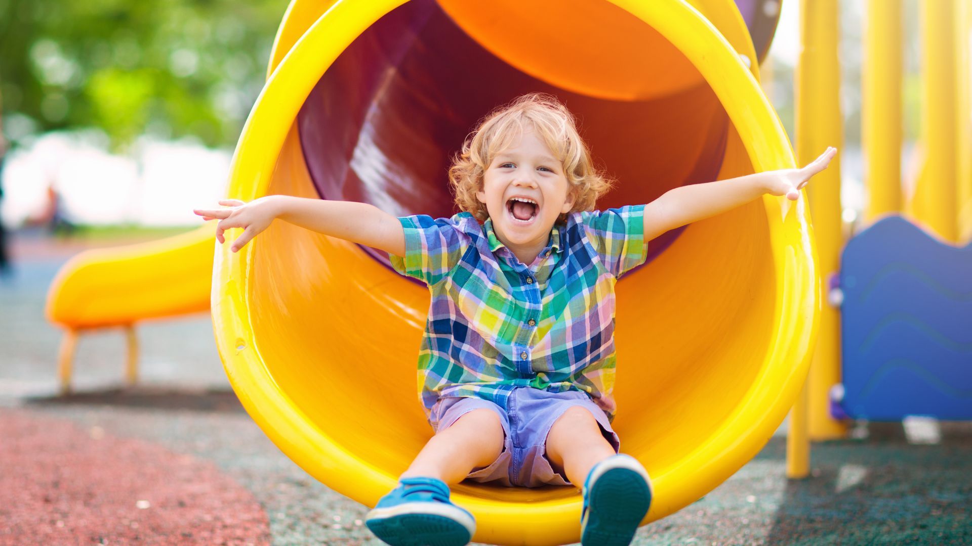 Child joyfully sliding down a bright yellow slide in an indoor playground, perfect for kids' birthday parties in McAllen.